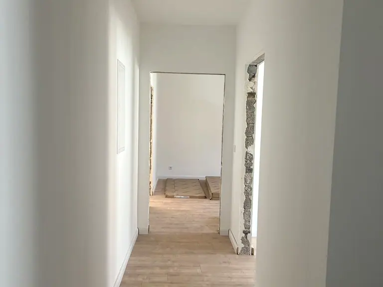 Renovierter Flur einer Wohnung am Pothmannsweg mit hellen Wänden, neuem Boden und Blick in die Zimmer